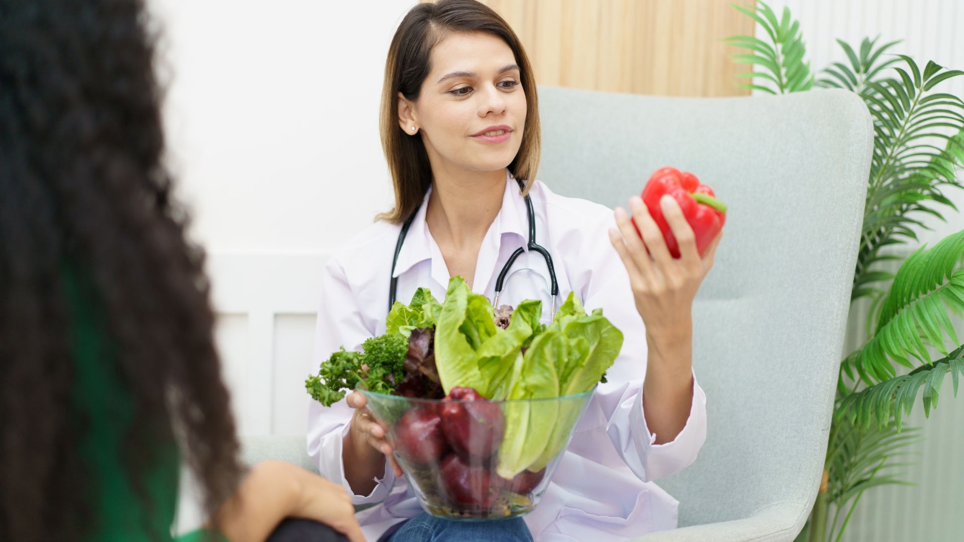 A woman sitting in a chair holding a bowl of vegetables